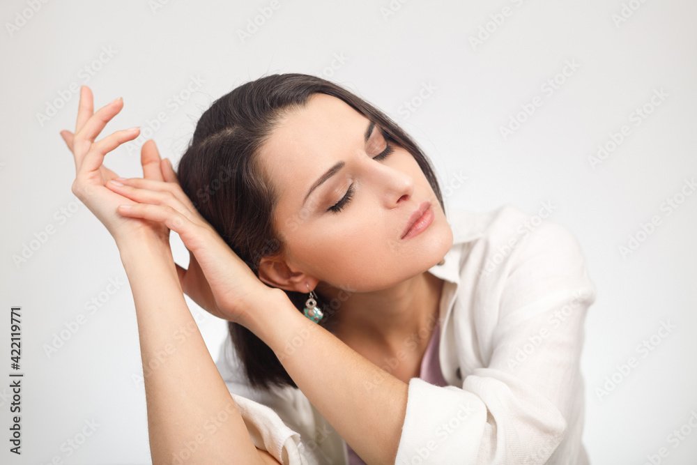 High-key studio portrait of a young brunette mixed race woman in light clothes with closed eyes. High-key studio portrait of a young brunette mixed race woman in light clothes with closed eyes.