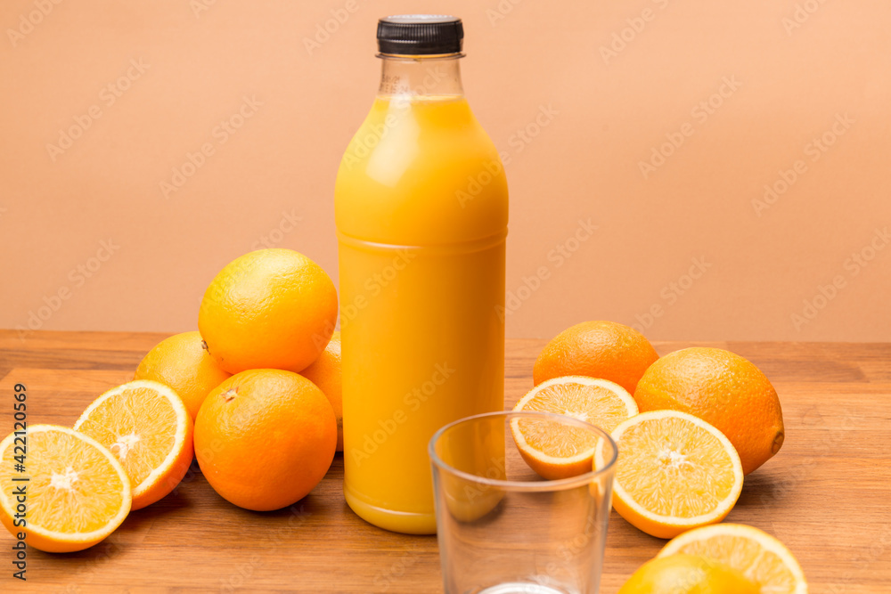 orange juice, oranges cut in half, transparent bottle with black cap filled with freshly squeezed orange juice, empty transparent glass on a wooden surface orange juice, oranges cut in half, transparent bottle with black cap filled with freshly squeezed orange juice, empty transparent glass on a wooden surface