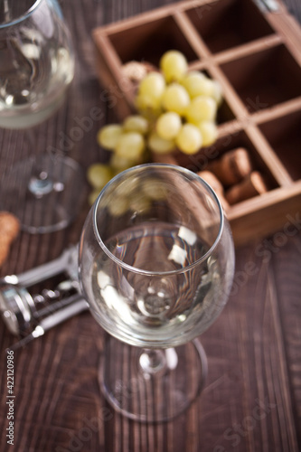 Glasses of white grape wine with grapes and wooden box on the background