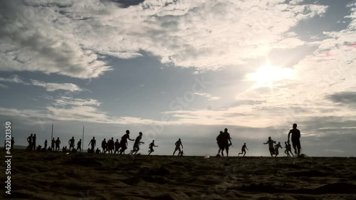African guys playing football on the ocean at sunset.