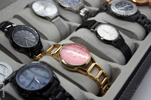 A variety of women's watches in a storage box.