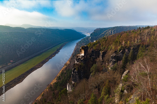 Aerial panorama view of Elbe River and sandstone mountains in Saxon Switzerland National Park near Stadt Wehlen on a sunny winter day with blue sky cloud, Saxony, Germany