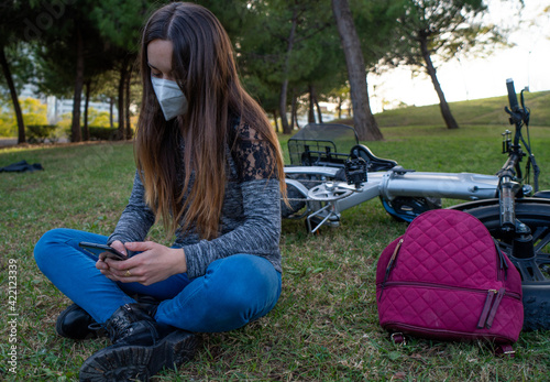 Girl with mask in the park with mobile.