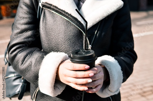 Shot of beautiful brunette girl with takeaway drink on the street. scarf and autumn coat in the city. view of business lady with a cup of coffee walking down the street.