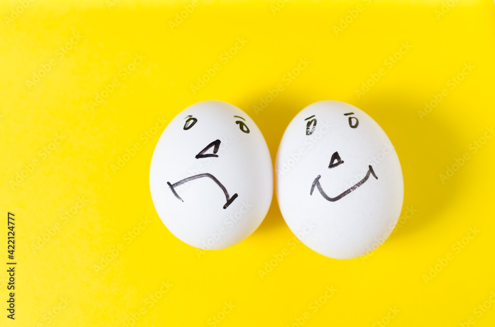 Fototapeta premium Eggs with funny and sad emotional faces, on a yellow background.