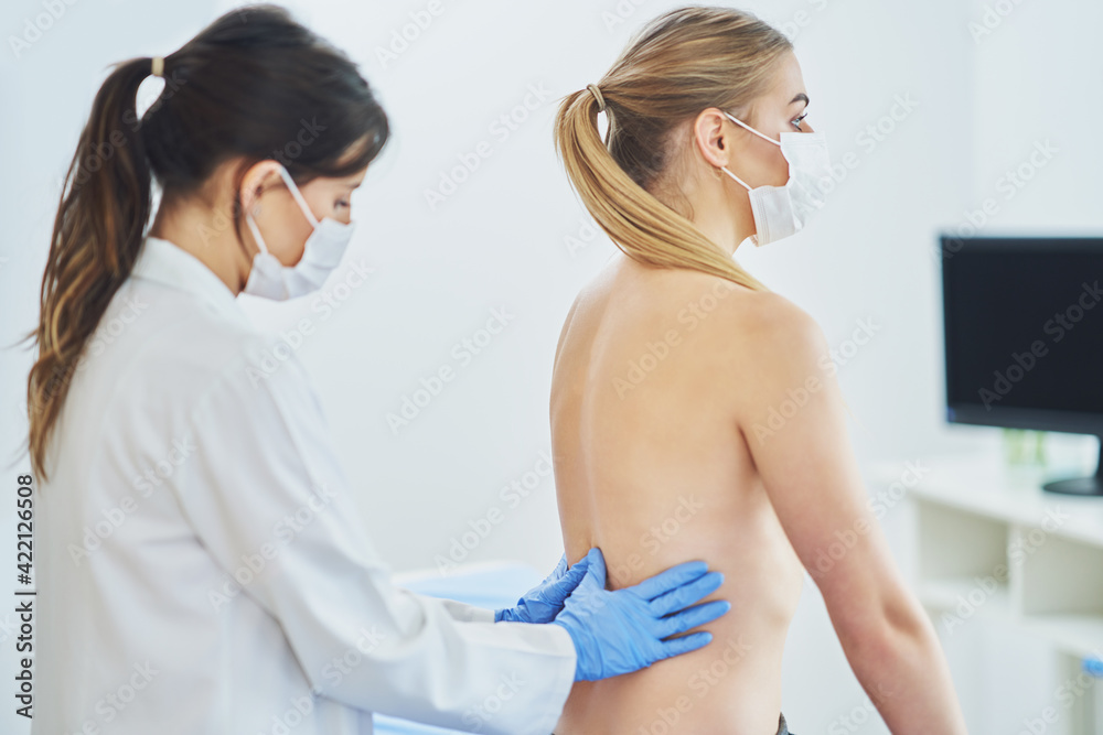 Obraz premium Doctor in mask checking up breast to her patient