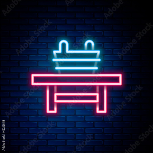 Glowing neon line Sauna bench with bucket icon isolated on brick wall background. Colorful outline concept. Vector