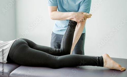 Physical therapy treatments for piriformis syndrome, physical therapist stretches female patient's buttocks muscle, post-isometric relaxation photo