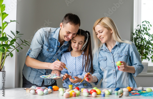 Happy easter family mother, father and children having fun paint and decorate eggs for holiday