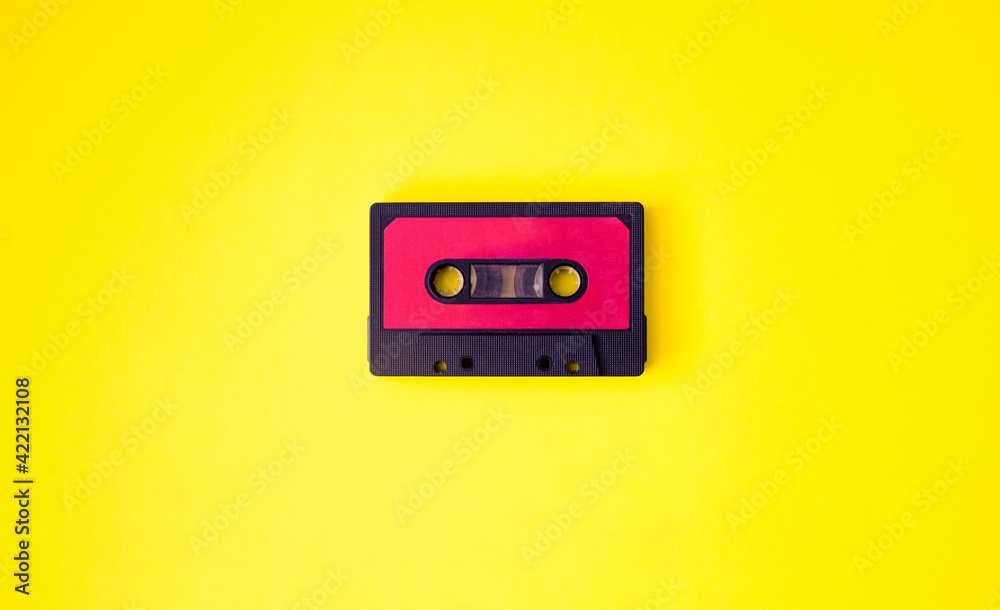 Black music cassette on yellow background. Space for text. Retro concept