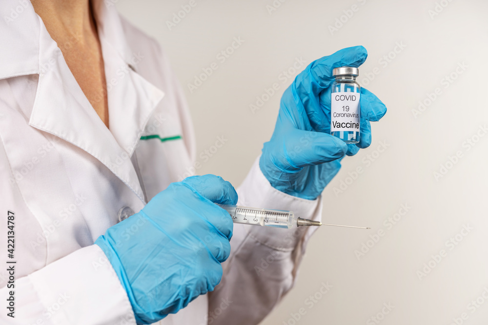 Vial withCOVID-19 vaccine and a syringe with a needle for injections for coronavirus infection in the hand of a doctor in a nitrile glove on a white background. Close-up. Concept fighting Coronavirus Vial withCOVID-19 vaccine and a syringe with a needle for injections for coronavirus infection in the hand of a doctor in a nitrile glove on a white background. Close-up. Concept fighting Coronavirus