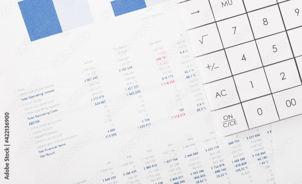 Financial charts and a calculator on the accountant's desk. Calculating profits, taxes, and paying employees salaries. Financial charts and a calculator on the accountant's desk. Calculating profits, taxes, and paying employees salaries.