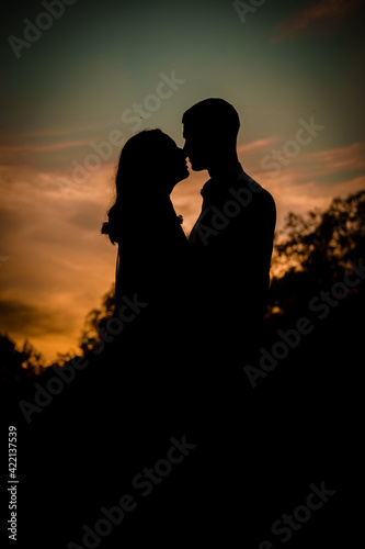 Silhouette of enamored man and woman at sunset.