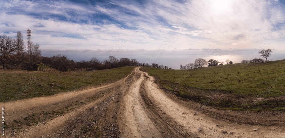 A gravel road leading toward horizon. Spectacular view on the sea and blue sky in the evening. Panoramic image
