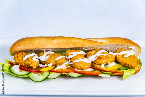 Baguette stuffed with turkey nuggets and vegetables. Food styling for street food. Closeup.