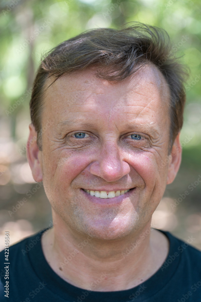 Portrait of a middle aged man resting on a background of green leaves in nature, closeup