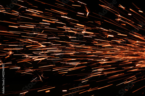 Glowing flow of sparks in the dark. Process of working with metal. Splatter.
