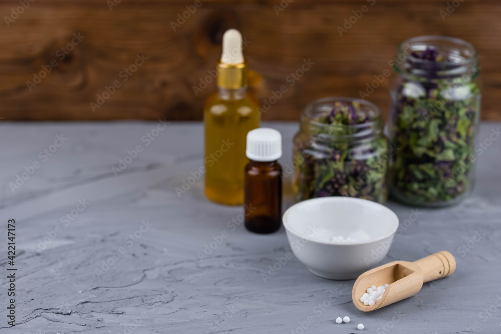Homeopathy alternative medicine eco concept - classical homeopathy pills. Homeopathic globules, natural organic aroma oil essence and healing herbs. Wooden background. 