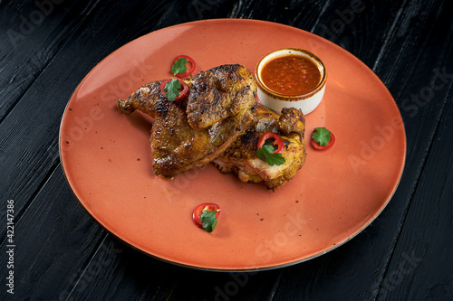 Georgian cuisine dish chicken tapaka on a plate, on wooden background. Grilled chicken. Top view photo