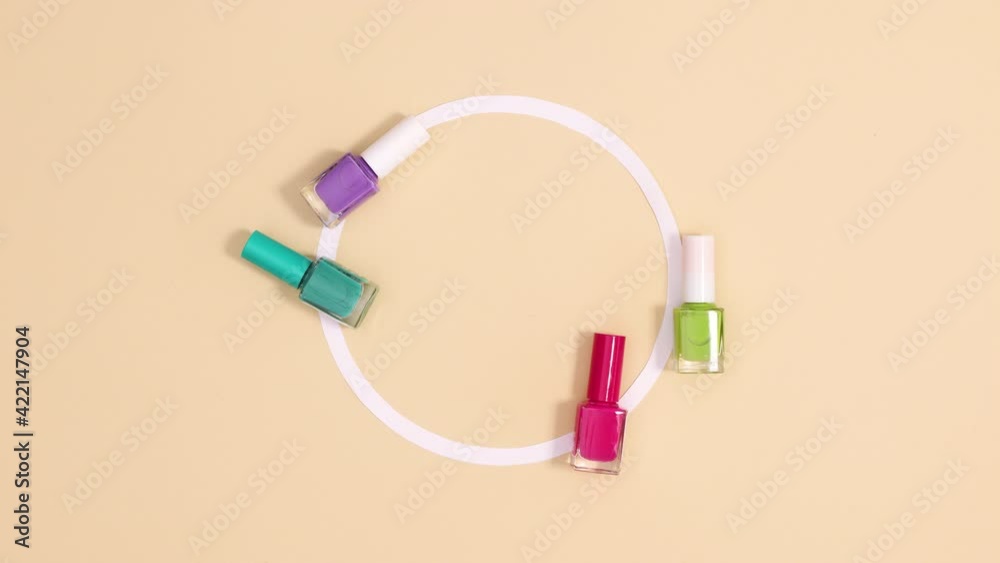 Pastel colored nail polishes bottles move around copy space circle on beige background. Stop motion Pastel colored nail polishes bottles move around copy space circle on beige background. Stop motion