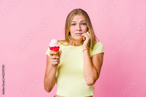 Young russian woman eating an ice cream isolated biting fingernails, nervous and very anxious.