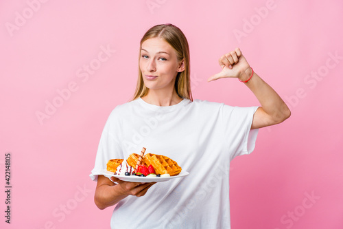 Young russian woman eating a waffle isolated feels proud and self confident, example to follow.