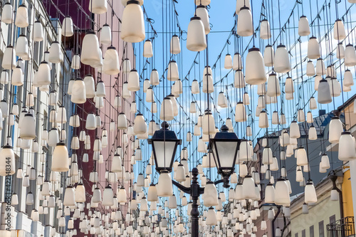 Decorations of Stoleshnikov lane in Moscow. Large garland from electric bulbs hangs above pedestrian street. Clear blue sky in the background. Travel in Russia theme. photo