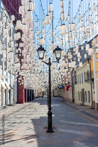 Decorations of Stoleshnikov lane in Moscow. Large garland from electric bulbs hangs above pedestrian street. Clear blue sky in the background. Travel in Russia theme. photo