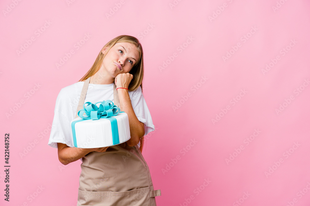 Young russian baker woman holding a delicious cake who feels sad and pensive, looking at copy space. Young russian baker woman holding a delicious cake who feels sad and pensive, looking at copy space.