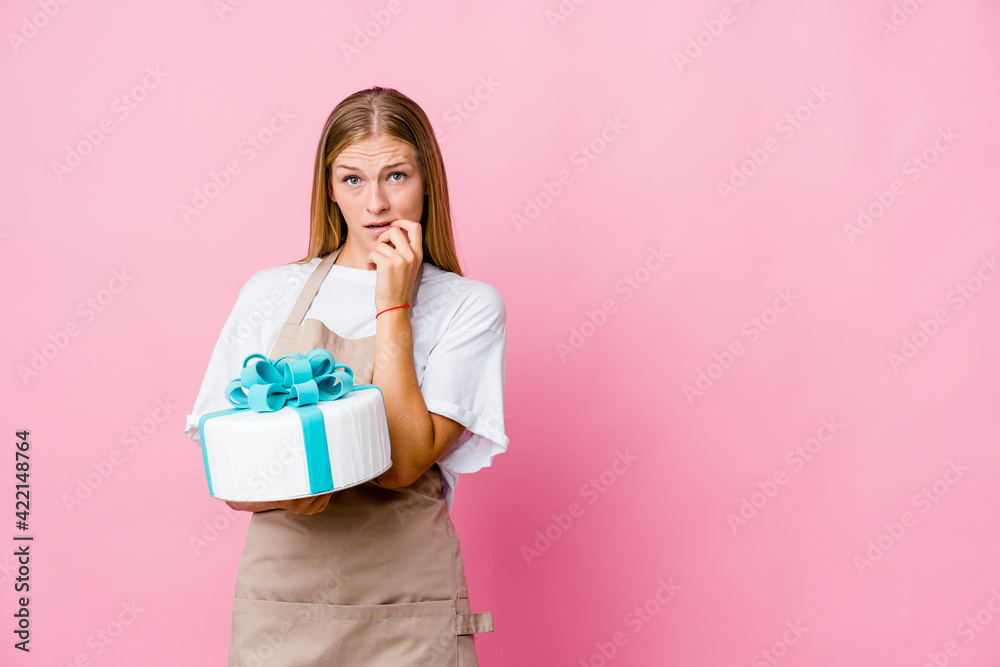 Young russian baker woman holding a delicious cake relaxed thinking about something looking at a copy space. Young russian baker woman holding a delicious cake relaxed thinking about something looking at a copy space.