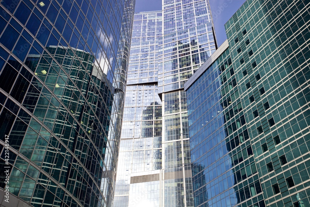 Office and residential skyscrapers facades close up. Reflections and glare on the glass facades of skyscrapers close-up. Futuristic parts of skyscrapers exterior design. Modern city architecture.