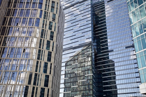 Office and residential skyscrapers facades close up. Reflections and glare on the glass facades of skyscrapers close-up. Futuristic parts of skyscrapers exterior design. Modern city architecture.