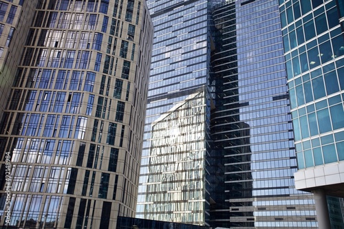 Office and residential skyscrapers facades close up. Reflections and glare on the glass facades of skyscrapers close-up. Futuristic parts of skyscrapers exterior design. Modern city architecture.