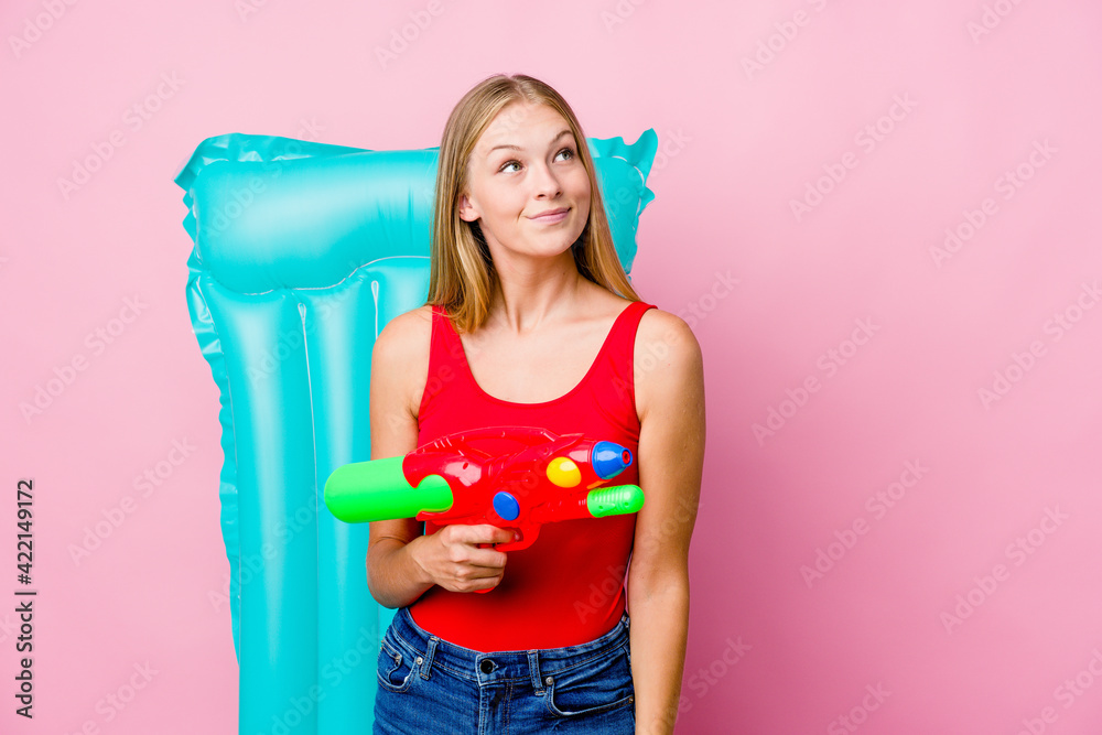 Young russian woman playing with a water gun with an air mattress dreaming of achieving goals and purposes
