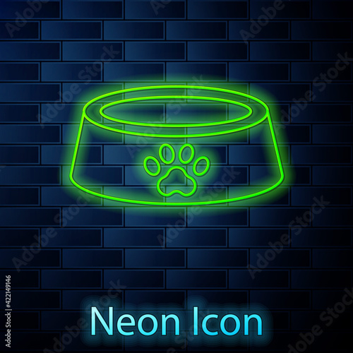 Glowing neon line Pet food bowl for cat or dog icon isolated on brick wall background. Dog or cat paw print. Vector