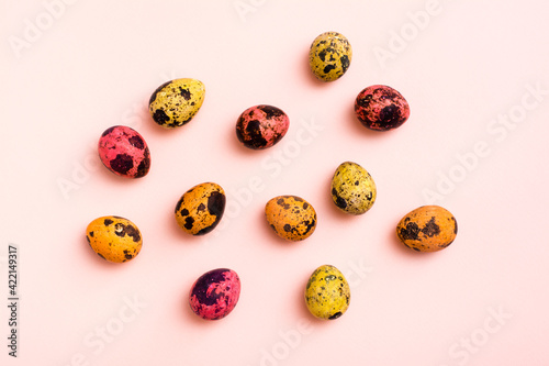 Happy Easter. Painted quail eggs on a pink background