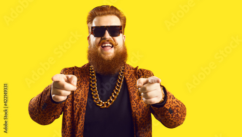 Happy guy in gold necklace and leopard suit pointing fingers at camera isolated on color background. Famous fashion designer, rich showbiz producer, casting director, funny celebrity says I choose you photo