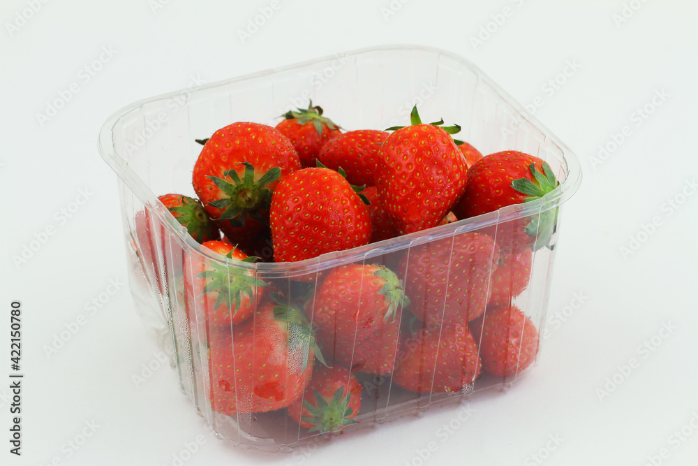 Fresh sweet strawberries in transparent plastic box on white background
