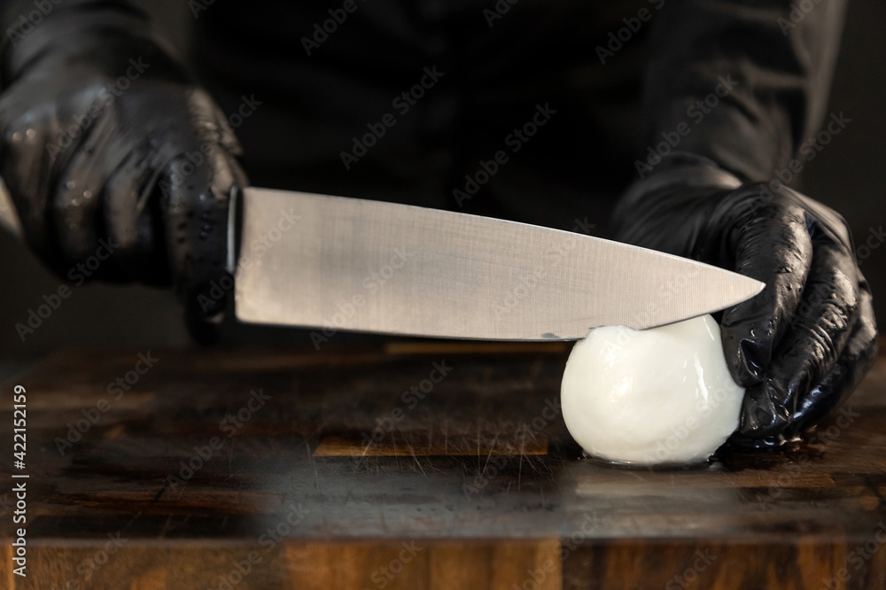 Sliced mozzarella with knife on kitchen board