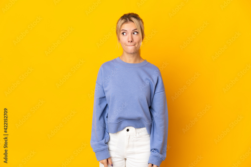 Young Russian woman isolated on yellow background having doubts while looking up Young Russian woman isolated on yellow background having doubts while looking up