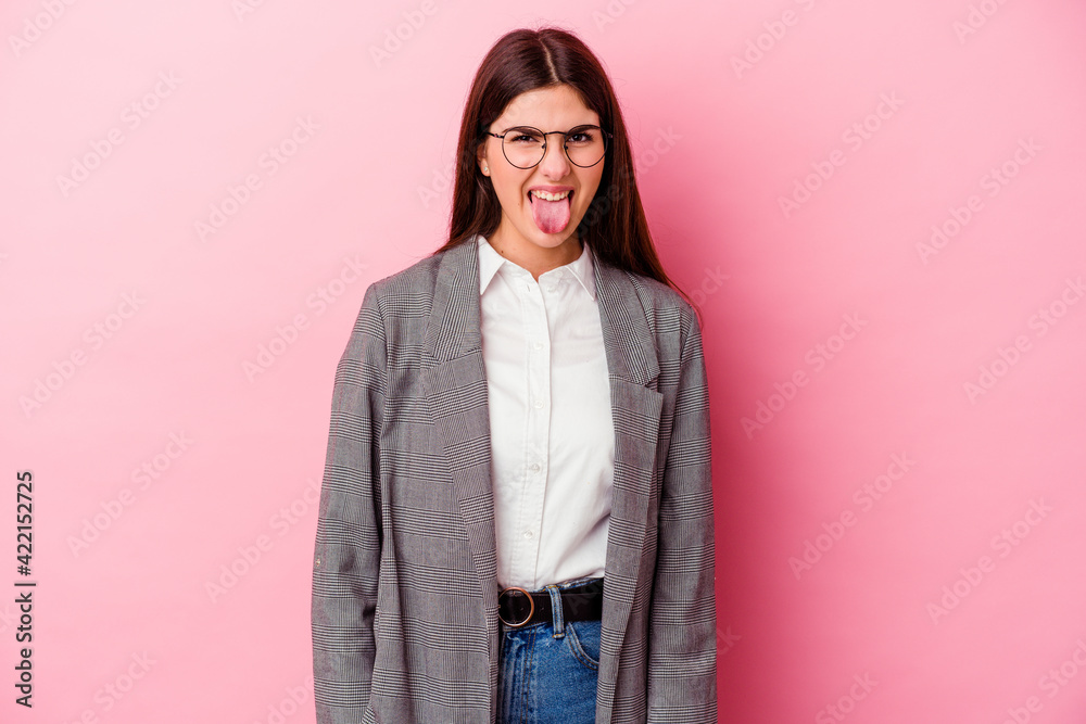 Young caucasian business woman isolated on pink background funny and friendly sticking out tongue.