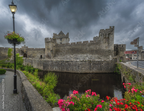 Old vintage lit street lamp in front of Cahir castle and moat in Cahir town with dramatic, storm sky in background, County Tipperary, Ireland photo