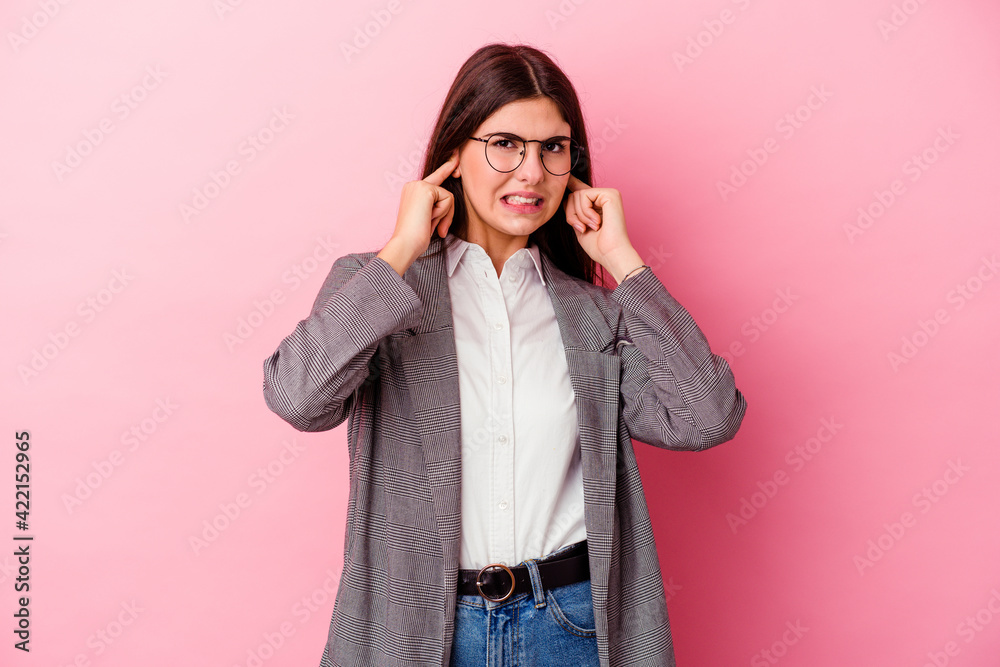 Young caucasian business woman isolated on pink background covering ears with hands. Young caucasian business woman isolated on pink background covering ears with hands.