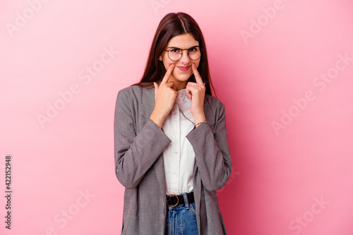 Young caucasian business woman isolated on pink background doubting between two options.