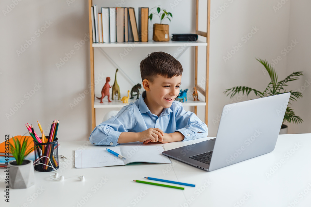 Kid via laptop talking with teacher during online studying at home. Elementary school e-learning via video call. Funny boy doing homework using internet and gadget Kid via laptop talking with teacher during online studying at home. Elementary school e-learning via video call. Funny boy doing homework using internet and gadget