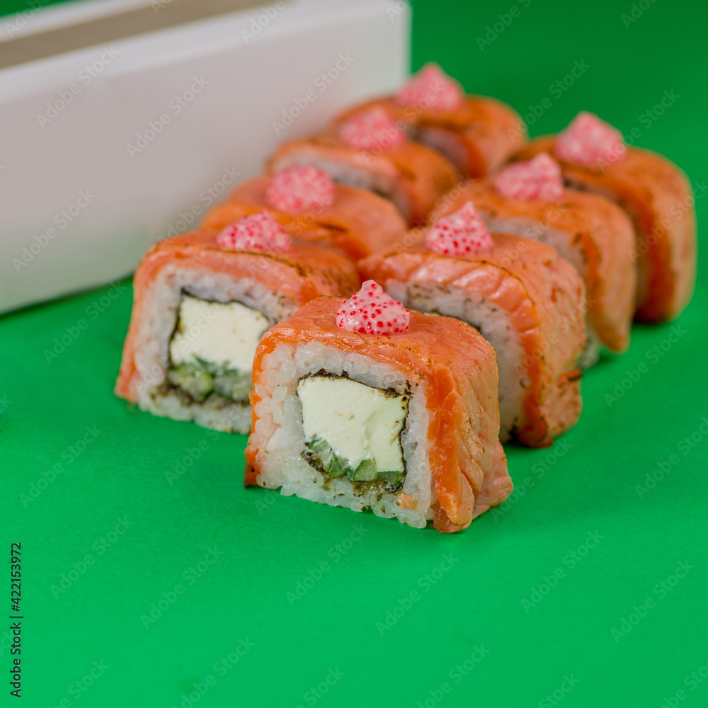 Sushi with salmon and cream cheese on a green background. Close-up Sushi with salmon and cream cheese on a green background. Close-up