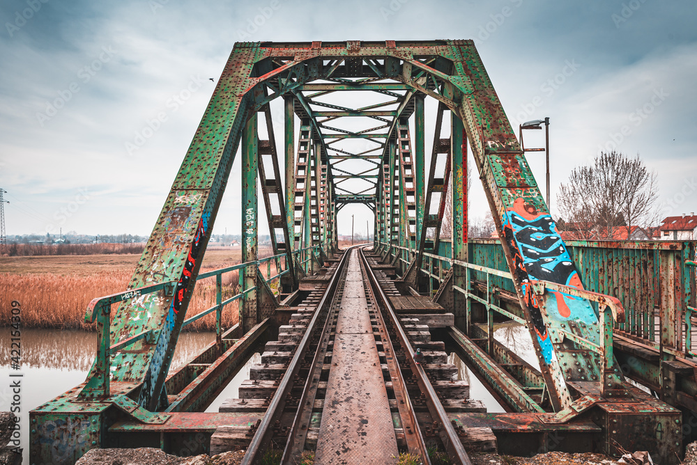 An old rusty railway bridge with a dramatic sky