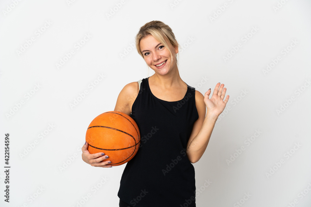 Young Russian woman playing basketball isolated on white background saluting with hand with happy expression