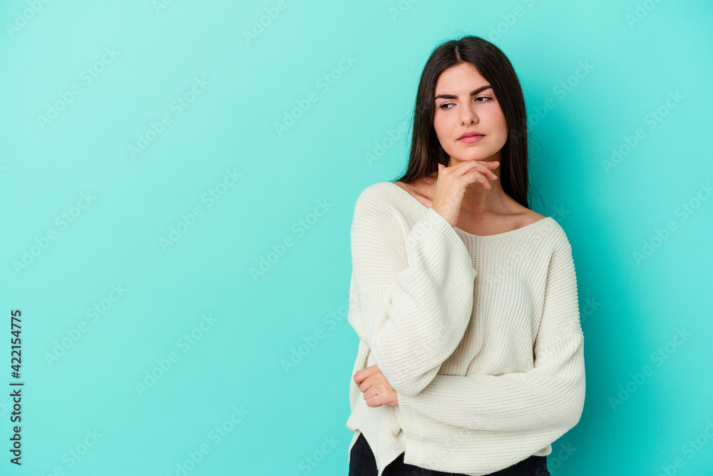 Young caucasian woman isolated on blue background looking sideways with doubtful and skeptical expression. Young caucasian woman isolated on blue background looking sideways with doubtful and skeptical expression.