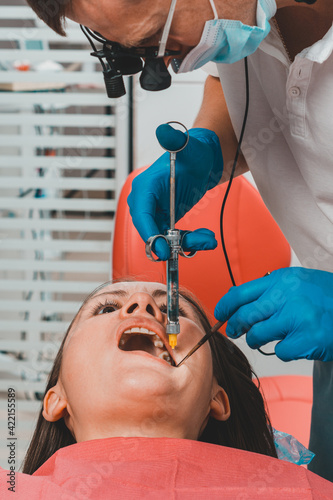The dentist with the help of a carpule syringe injects anesthesia into the patient's gums, local anesthesia.